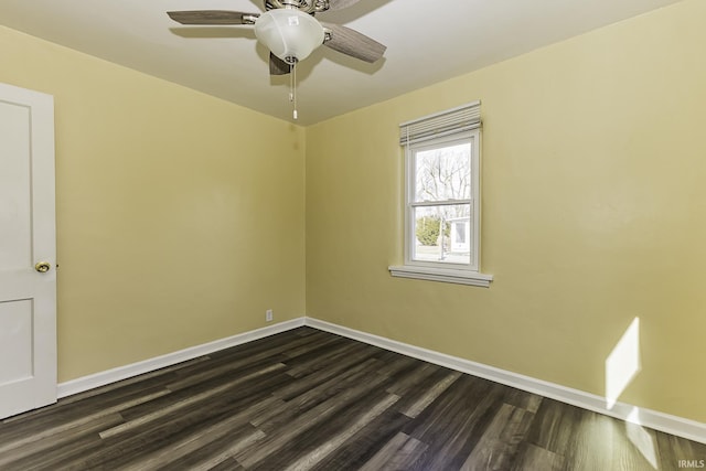 empty room with dark wood finished floors, a ceiling fan, and baseboards