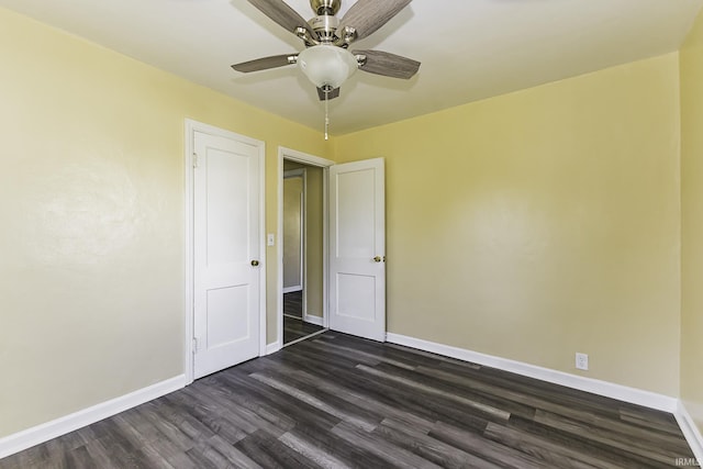 empty room featuring baseboards, dark wood-style floors, and a ceiling fan