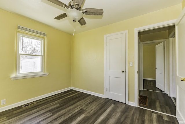 unfurnished bedroom with visible vents, baseboards, dark wood-type flooring, and ceiling fan