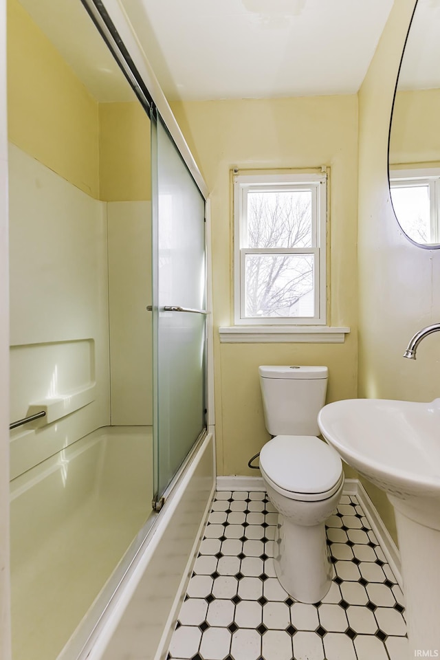 full bath with tile patterned floors, toilet, baseboards, and a wealth of natural light