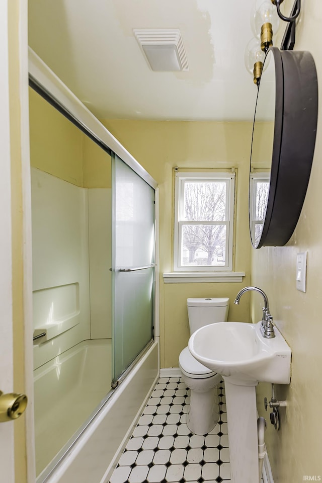 bathroom with tile patterned floors, visible vents, toilet, shower / bath combination with glass door, and baseboards