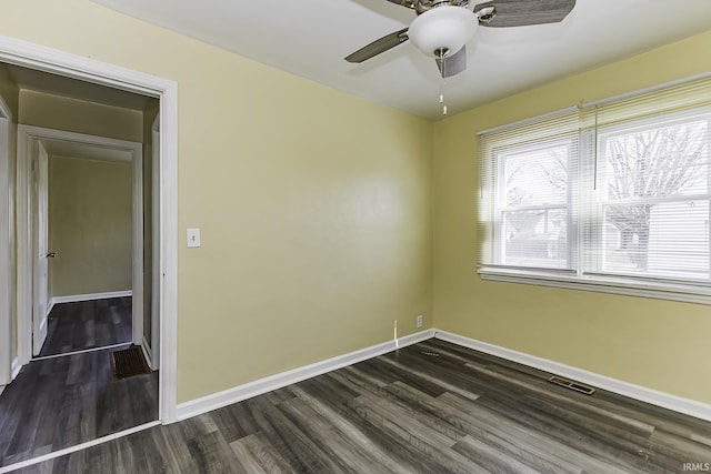 unfurnished room with visible vents, baseboards, and dark wood-type flooring