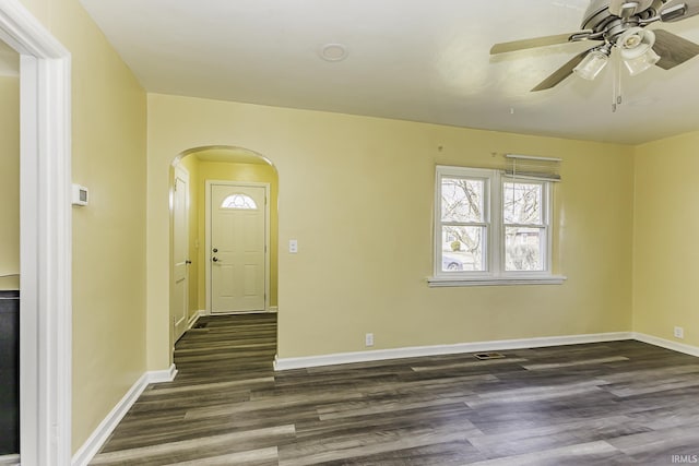 entryway featuring arched walkways, baseboards, dark wood-type flooring, and ceiling fan