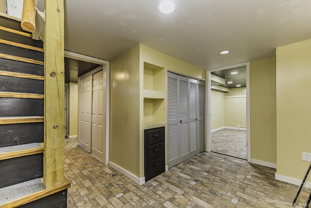 corridor with recessed lighting, baseboards, and brick floor