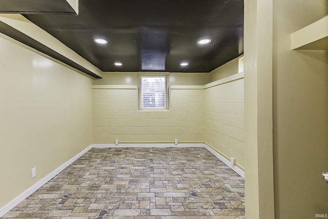 below grade area featuring brick floor, recessed lighting, and baseboards