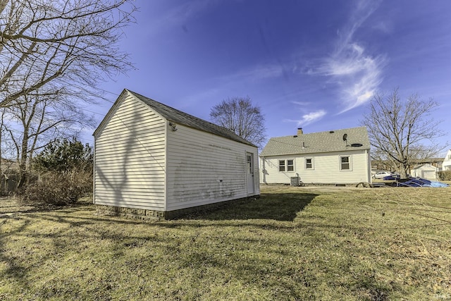 back of property featuring an outdoor structure and a yard