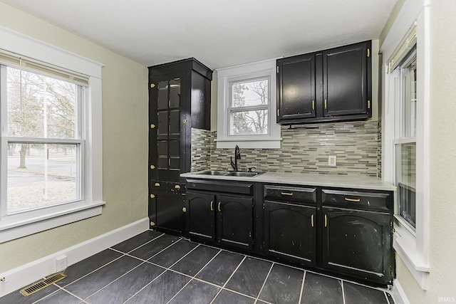 kitchen with visible vents, a healthy amount of sunlight, dark cabinetry, and a sink