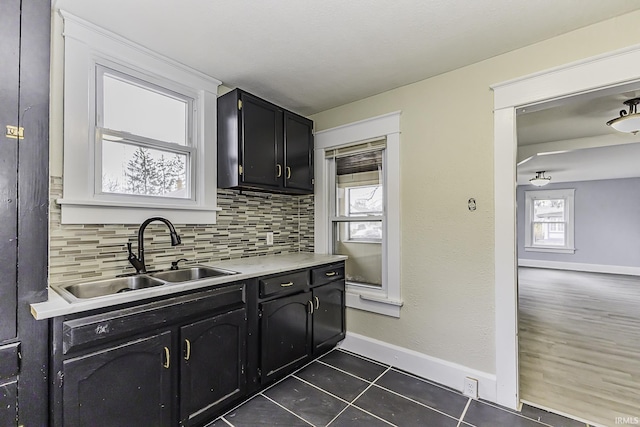 kitchen featuring dark tile patterned flooring, a sink, light countertops, decorative backsplash, and dark cabinets