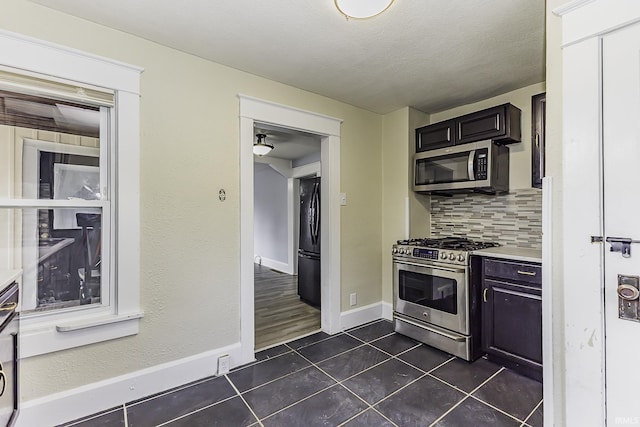 kitchen featuring tasteful backsplash, baseboards, dark tile patterned floors, light countertops, and appliances with stainless steel finishes