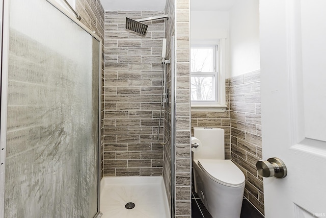 full bathroom featuring toilet, tile walls, and a stall shower