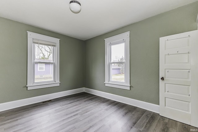 spare room with baseboards and wood finished floors