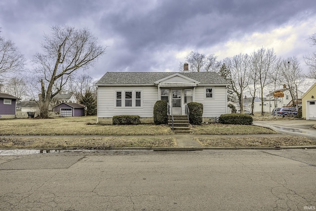 bungalow-style home featuring roof with shingles and a chimney