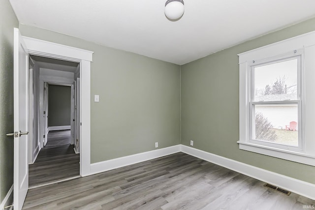 spare room with visible vents, baseboards, and wood finished floors