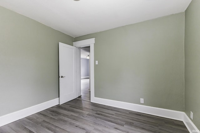 empty room featuring dark wood-style floors and baseboards