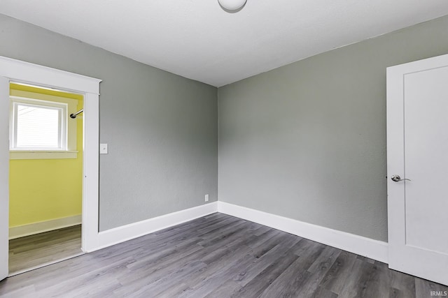 spare room featuring baseboards and dark wood-style flooring