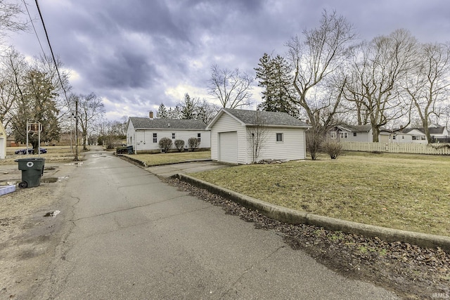 exterior space featuring an outbuilding, fence, driveway, a yard, and a chimney