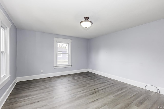 empty room with visible vents, wood finished floors, and baseboards