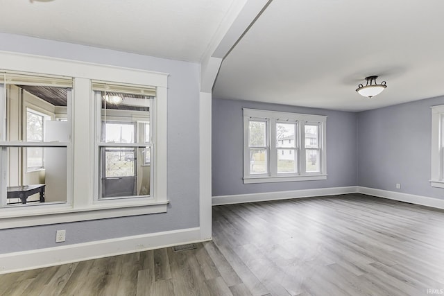 unfurnished room featuring visible vents, baseboards, and wood finished floors