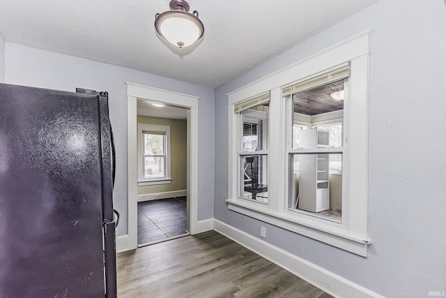 hall featuring a textured ceiling, baseboards, and wood finished floors