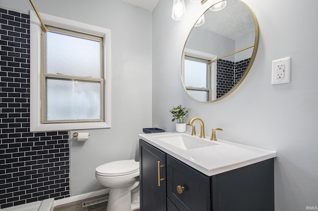 bathroom with vanity, visible vents, a tile shower, a textured ceiling, and toilet