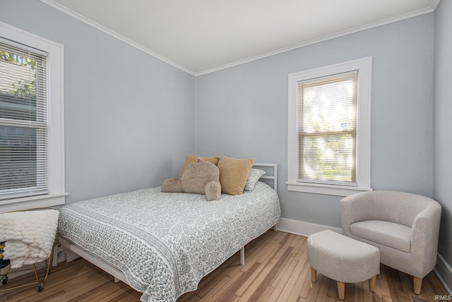 bedroom with hardwood / wood-style floors, crown molding, and baseboards