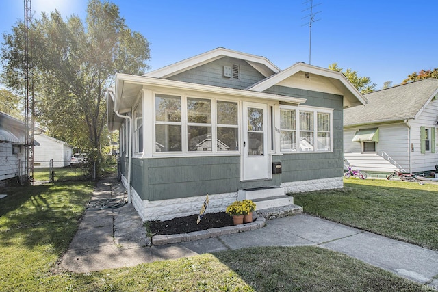 view of front of house featuring entry steps, a front yard, fence, and a sunroom