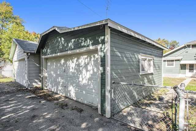 view of home's exterior with an outbuilding, a shingled roof, and fence