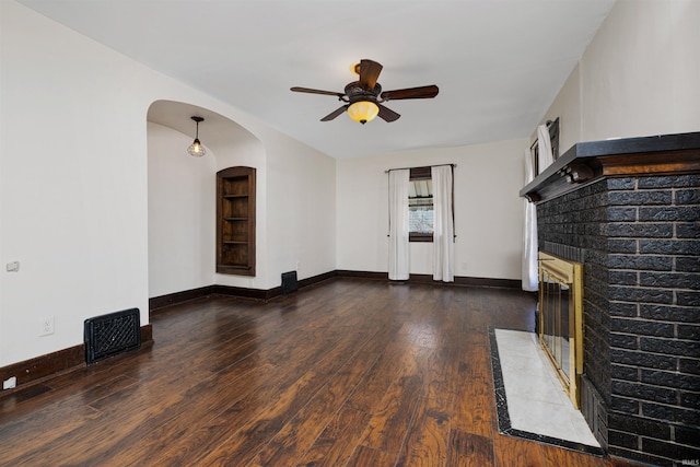 unfurnished living room featuring visible vents, a brick fireplace, baseboards, ceiling fan, and hardwood / wood-style flooring