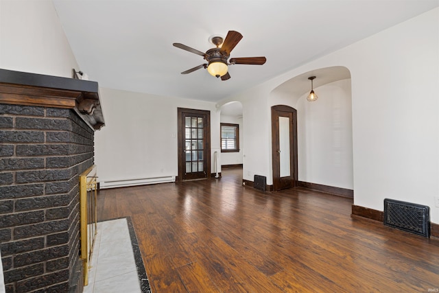 unfurnished living room with visible vents, a baseboard heating unit, hardwood / wood-style floors, arched walkways, and a ceiling fan