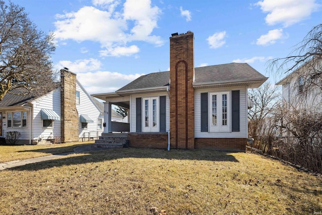 rear view of house with a lawn, roof with shingles, and a chimney