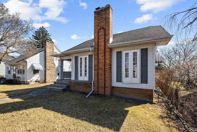 back of property featuring entry steps, a chimney, and a yard