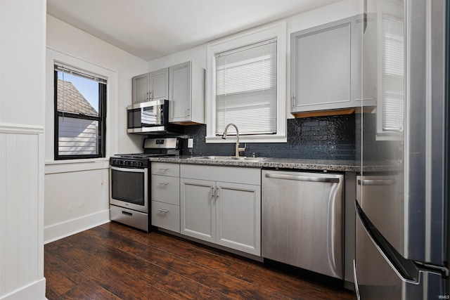 kitchen with a sink, tasteful backsplash, appliances with stainless steel finishes, and dark wood finished floors