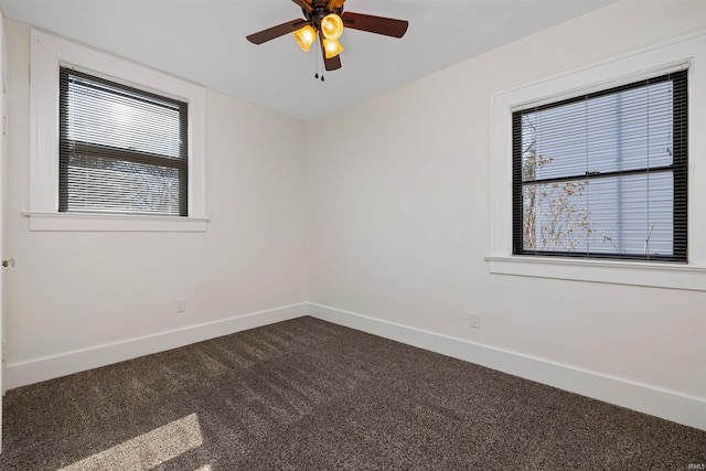 empty room featuring dark carpet, a ceiling fan, and baseboards