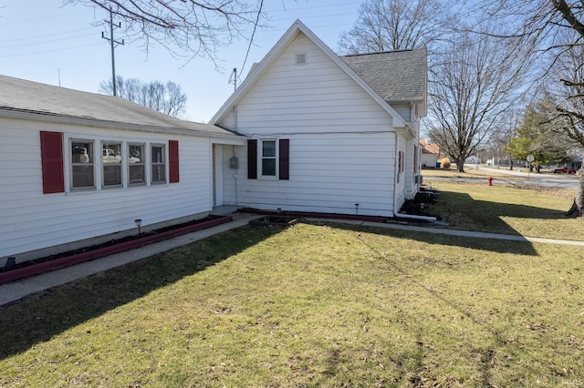 back of property with a lawn and roof with shingles