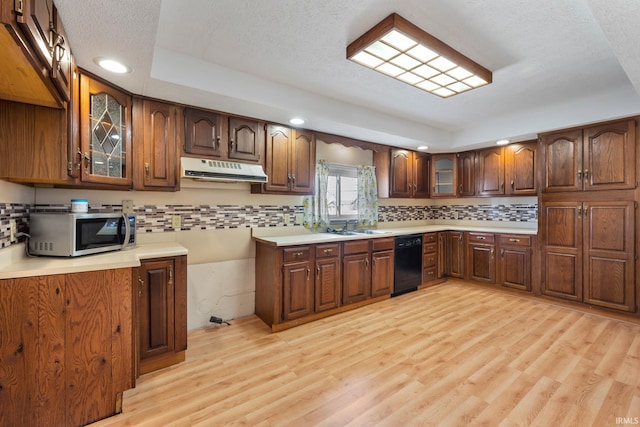 kitchen featuring decorative backsplash, stainless steel microwave, ventilation hood, and light wood-type flooring