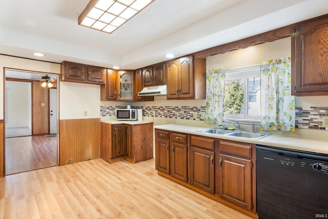 kitchen featuring under cabinet range hood, light wood-style flooring, dishwasher, and a sink