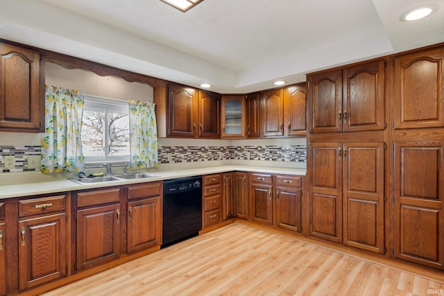 kitchen with dishwasher, light countertops, light wood finished floors, and a sink