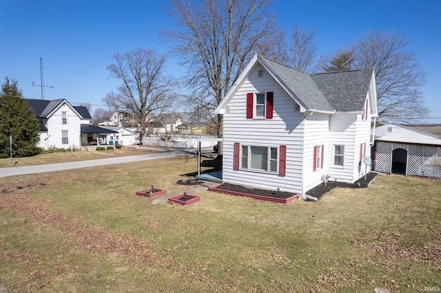 view of side of property featuring a lawn and a shingled roof