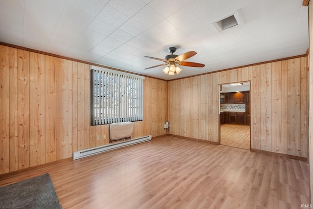 spare room with ceiling fan, crown molding, a baseboard heating unit, and light wood-style floors