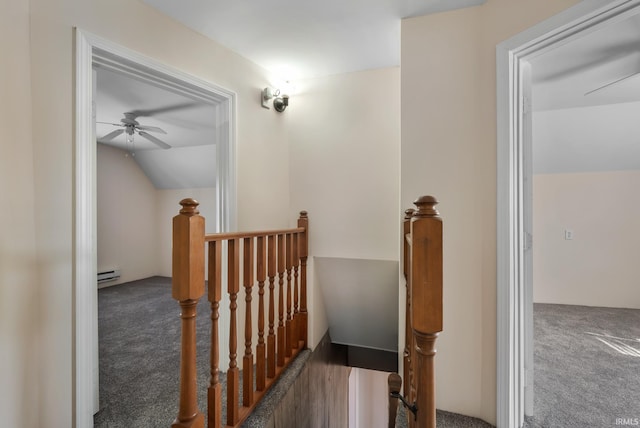 hallway featuring lofted ceiling, an upstairs landing, baseboard heating, and carpet floors