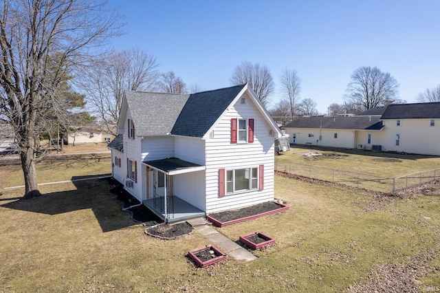 exterior space featuring a lawn, roof with shingles, and fence