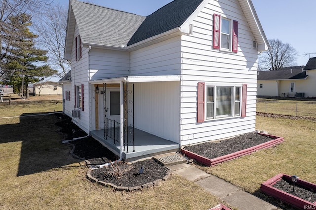 view of home's exterior with a yard, fence, and roof with shingles