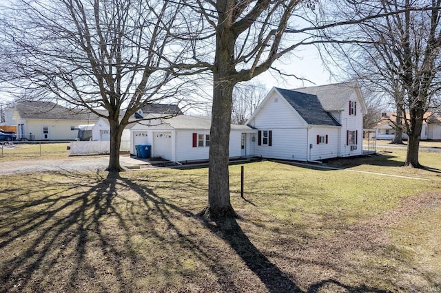 exterior space with fence, driveway, an attached garage, a yard, and a shingled roof