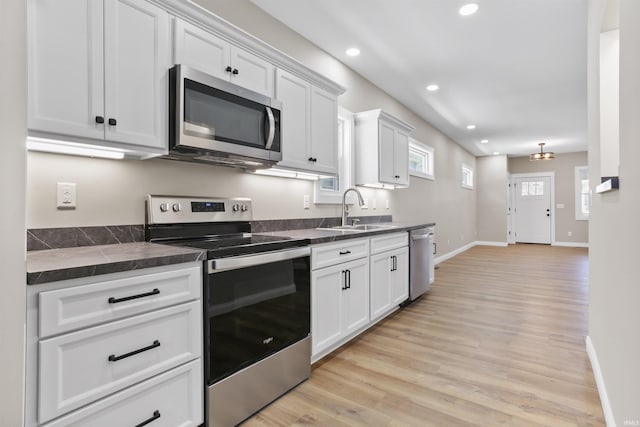 kitchen featuring dark countertops, recessed lighting, appliances with stainless steel finishes, and a sink