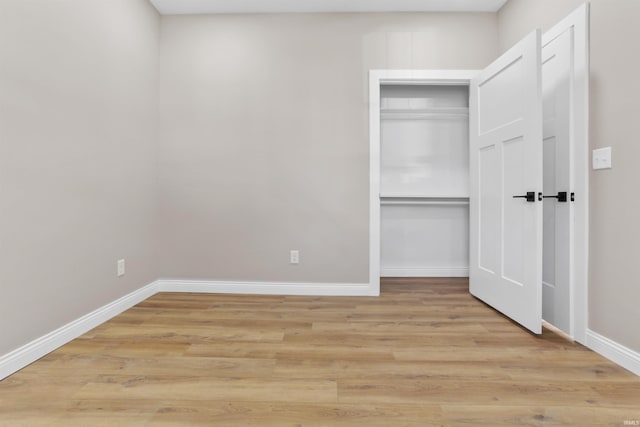 unfurnished bedroom featuring light wood-style flooring, baseboards, and a closet