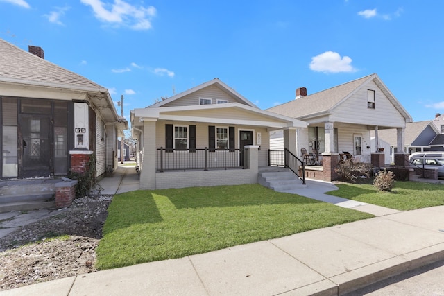 bungalow-style house with brick siding, covered porch, and a front yard