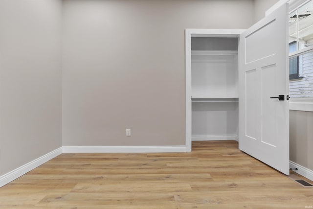 unfurnished bedroom with light wood-style flooring, visible vents, baseboards, and a closet