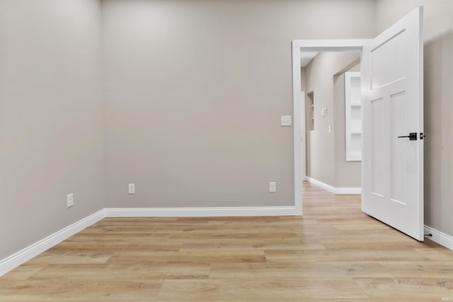 spare room featuring baseboards and light wood-style floors