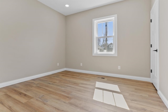 empty room featuring light wood-style flooring, visible vents, and baseboards