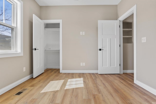 unfurnished bedroom with a closet, baseboards, visible vents, and light wood finished floors